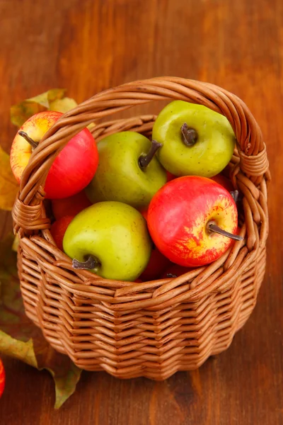 Pequeñas manzanas en canasta de mimbre sobre fondo de madera —  Fotos de Stock