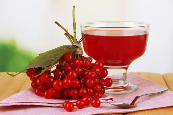 Красные ягоды вибурнума и чаши с вареньем на столе на ярком фоне — стоковое фото