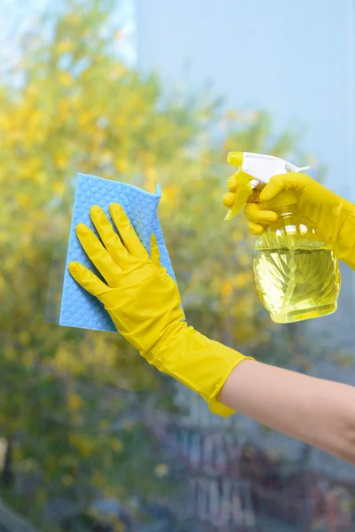 Mãos com spray limpando a janela — Fotografia de Stock