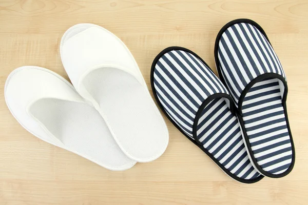 Striped and white slippers on wooden background — Stock Photo, Image
