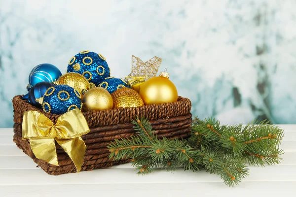 Decoraciones navideñas en cesta y ramas de abeto sobre mesa sobre fondo brillante — Foto de Stock