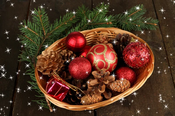 Christmas decorations in basket and spruce branches on wooden background — Stock Photo, Image