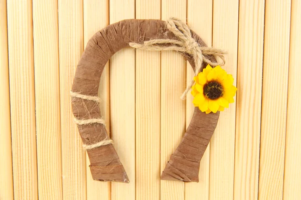 Decorative horseshoe of straw with sunflower, on wooden background — Stock Photo, Image