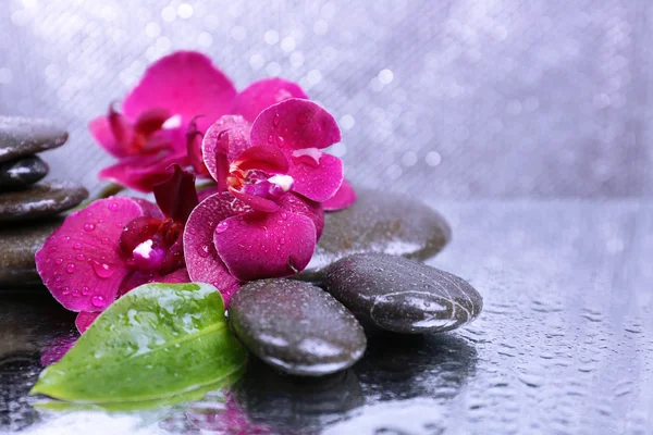 Composition with beautiful blooming orchid with water drops and spa stones, on light color background — Stock Photo, Image