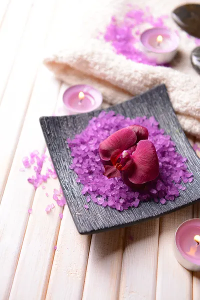 Stilleben med vackra blommande orkidé blomma, handduk och skål med havssalt, på färg trä bakgrund — Stockfoto