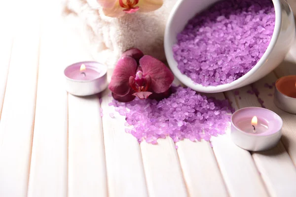 Bodegón con hermosa flor de orquídea, toalla y tazón con sal marina, sobre fondo de madera de color — Foto de Stock