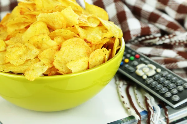 Chips in Schüssel, Zeitschriften, Plaid und TV-Fernbedienung Nahaufnahme — Stockfoto