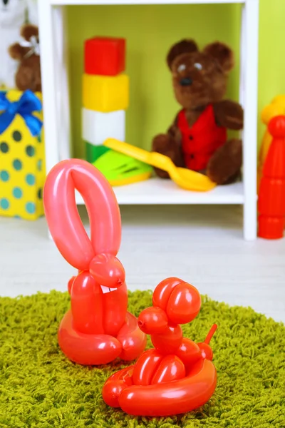 Прості тварини на повітряній кулі та інші іграшки на полицях, на яскравому фоні — стокове фото