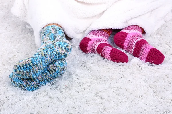 Piernas en calcetines de colores sobre fondo de alfombra blanca — Foto de Stock