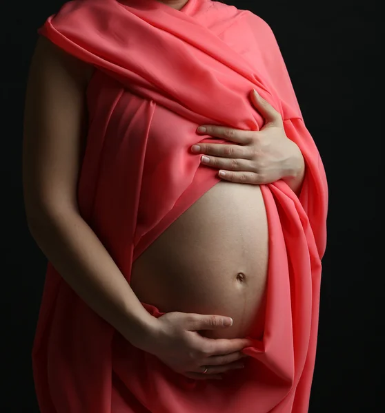 Młoda kobieta w ciąży z korala materiał na czarnym tle — Zdjęcie stockowe