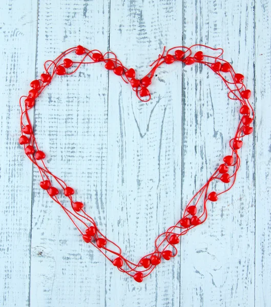 Heart-shaped beads on string on wooden background — Stock Photo, Image