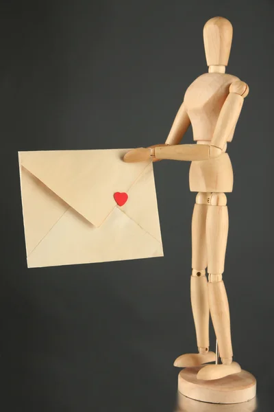 Wooden mannequin holding envelope on table on gray background — Stock Photo, Image