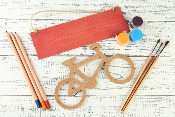 Decorative bicycle with drawing set on wooden background