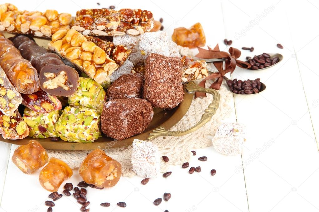 Tasty oriental sweets on tray, on white wooden background