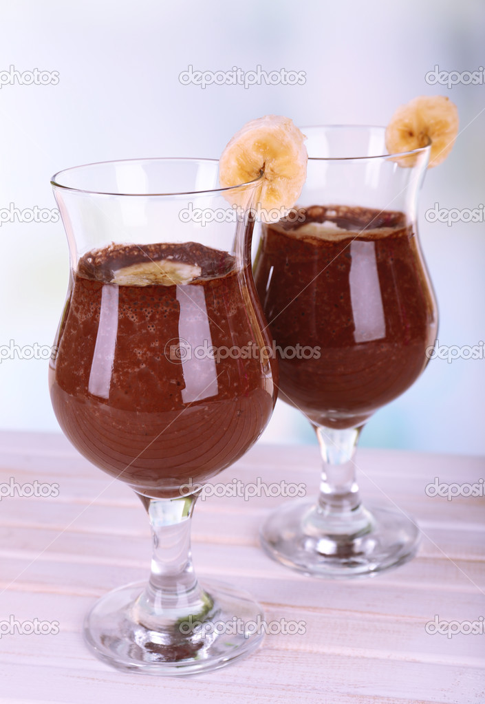 Cocktails with banana and chocolate on table on light background