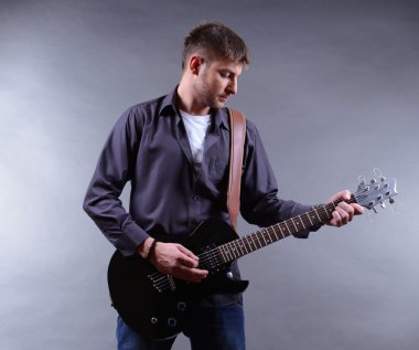 genç müzisyen gri arka plan üzerinde gitar çalmak