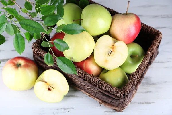 Juicy apples in basket on wooden table — Stock Photo, Image