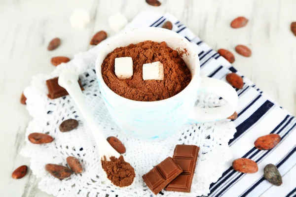 Poeder van de cacao in cup op servetten op houten tafel — Stockfoto