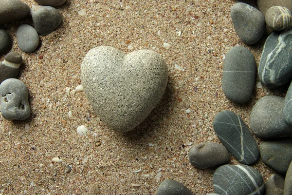 Szary kamień w kształcie serca, na tle piasek — Zdjęcie stockowe