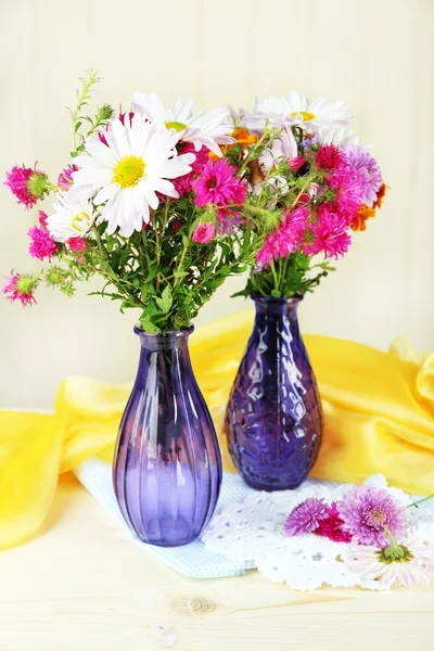 Wildflowers in glass vases on table on light background — Stock Photo, Image