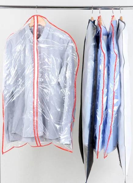 Office mannelijke kleding in gevallen voor het opslaan op hangers, op grijze achtergrond — Stockfoto
