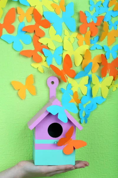 Papíru motýli létají z budky na pozadí zelené zdi — Stock fotografie