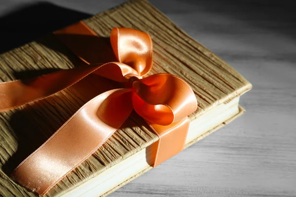 Livro envolto com fita de cor, na cor de fundo de madeira — Fotografia de Stock