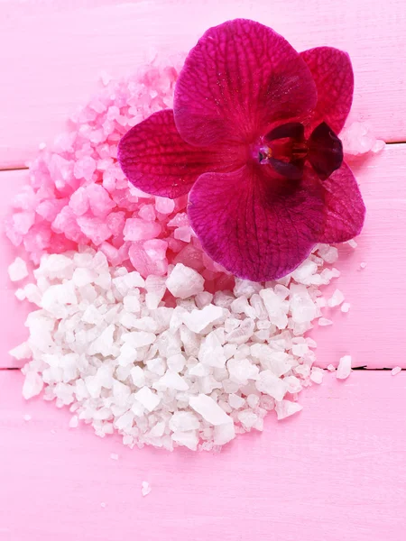 Красивый цветущий цветок орхидеи и куча морской соли, на цветном деревянном фоне — стоковое фото