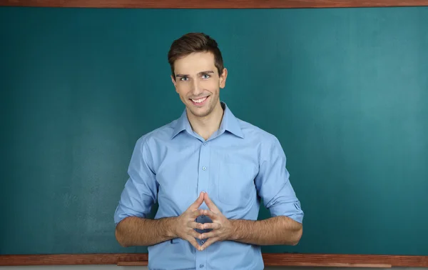 Young teacher near chalkboard in school classroom — Stock Photo, Image