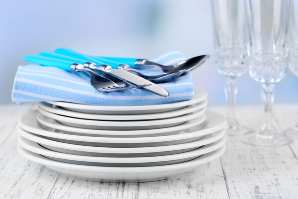 Clean dishes on wooden table on light background