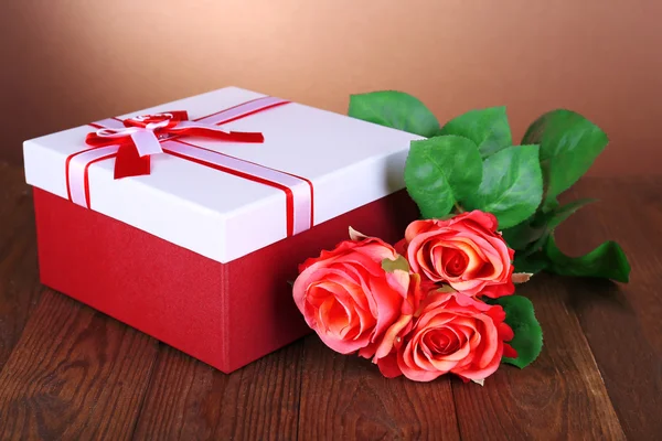 Beautiful gift box with flowers on table on brown background — Stock Photo, Image