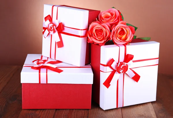 漂亮的礼品盒用棕色背景上的桌子上的花 — 图库照片
