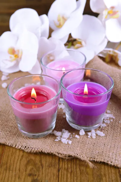 Composição com belas velas coloridas, sal marinho e flores de orquídeas, em fundo de madeira — Fotografia de Stock