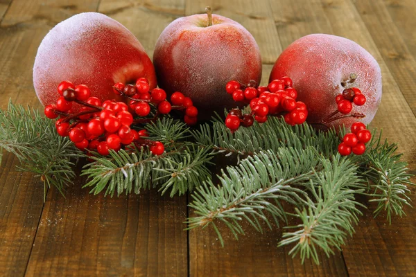 Červená jablka s jedle větev a bobule na dřevěné pozadí — Stock fotografie
