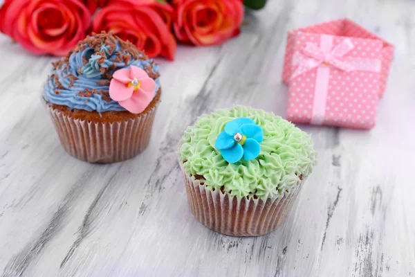 Ízletes cupcakes vaj tejszín, színes fából készült háttér — Stock Fotó