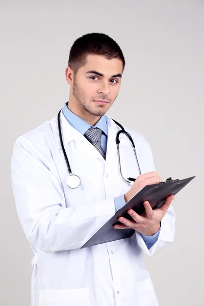Klasör, gri arka plan üzerinde duran erkek doktor — Stok fotoğraf