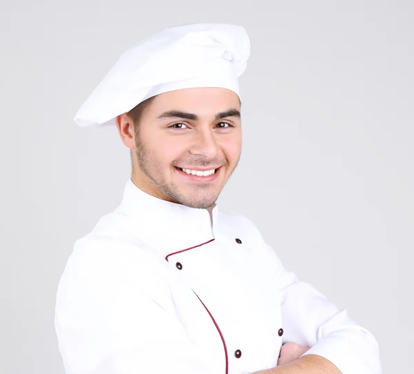Professionell kock i vit uniform och hatt, på grå bakgrund — Stockfoto