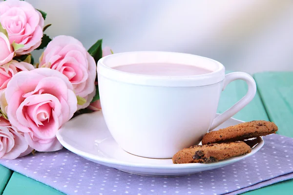 Cocoa drink and cookies on wooden table, on bright background