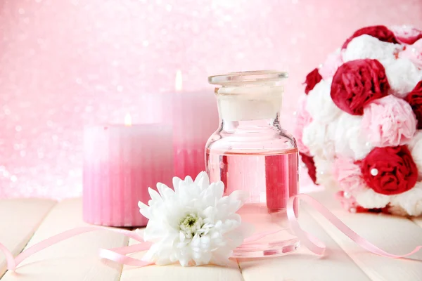 Стеклянная бутылка с цветовой сущностью, на розовом фоне — стоковое фото