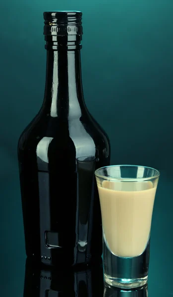 Liqueur Baileys en bouteille et verre sur fond bleu — Photo