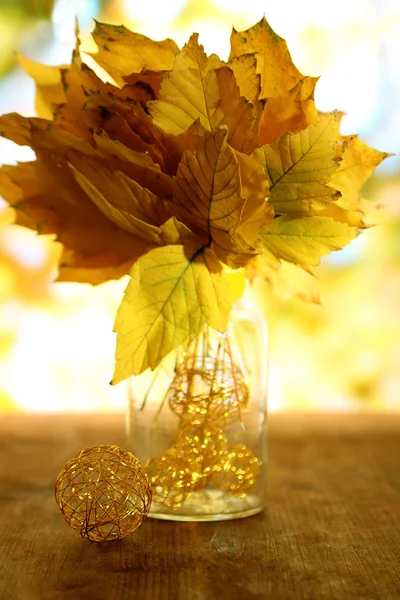 自然の背景に木製のテーブルの上の花瓶に鮮やかな秋の葉します。 — ストック写真