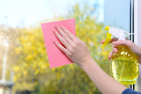 Mãos com spray limpando a janela — Fotografia de Stock