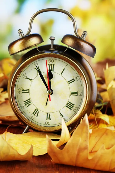 Παλιό ρολόι στα φύλλα του φθινοπώρου σε ξύλινο τραπέζι σε φυσικό φόντο — Φωτογραφία Αρχείου