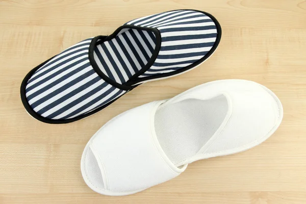 Striped and white slippers on wooden background — Stock Photo, Image