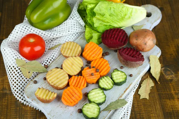 Belos legumes fatiados, na tábua de corte, no fundo de cor — Fotografia de Stock