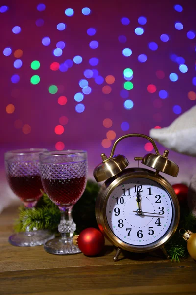 Copas de vino, despertador retro y decoración navideña sobre fondo brillante — Foto de Stock