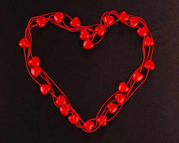 Heart-shaped beads on string on fabric background — Stock Photo, Image