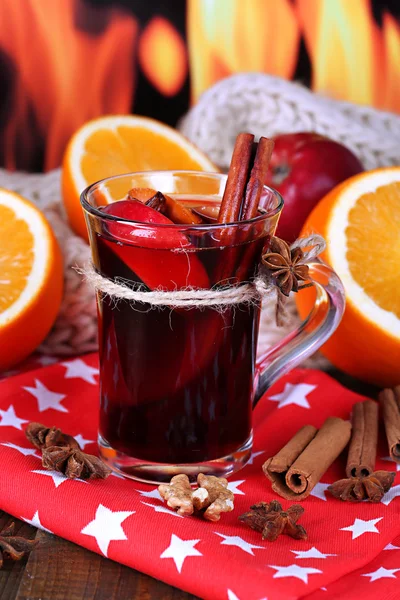 Fragrant mulled wine in glass on napkin on fire background — Stock Photo, Image