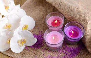 güzel renkli mumlar, deniz tuzu ve ahşap zemin üzerinde orkide çiçekleri ile kompozisyon