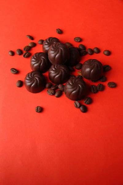 Caramelle al cioccolato e chicchi di caffè, su sfondo rosso — Foto Stock